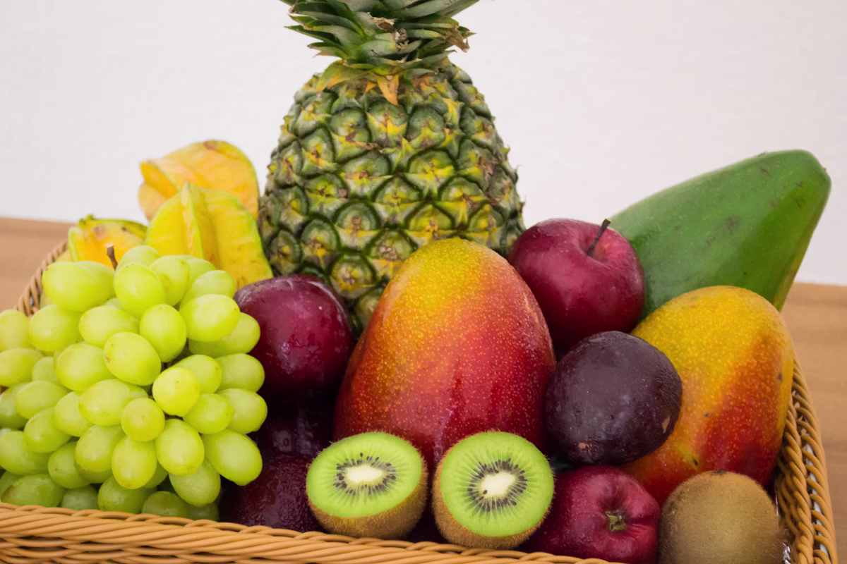 An assortment of fresh, whole fruits gathered in a woven basket